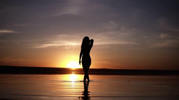 Silhouette of a Slender Girl Walking on the Water Do the Stains on the Surface
