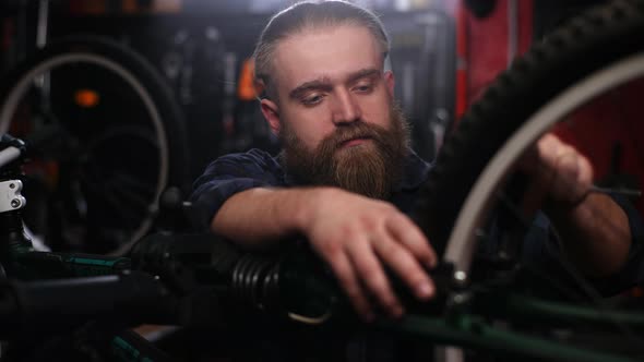 Tracking Shot of Handsome Bearded Bike Serviceman Tightening Bolt with Screwdriver Near Rear Wheel