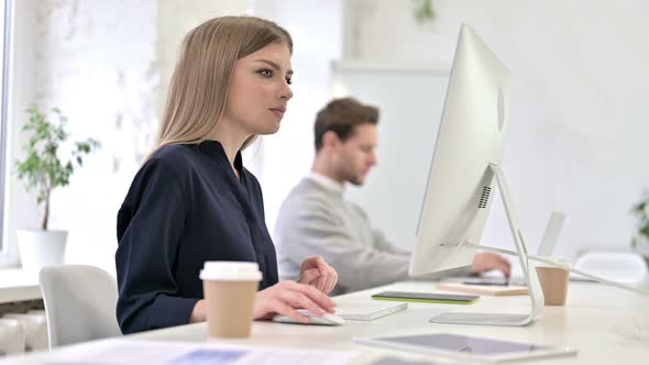 Young Creative Woman Working on Desktop and Smiling at the Camera