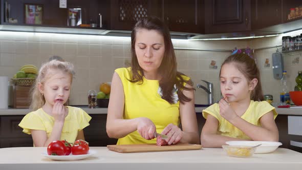 Mom and Children Cook in the Kitchen. Little Girl Smooths Pizza Dough. Mom Helps Children Cook Pizza