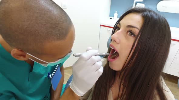 Close up of dental assistant examining woman's teeth