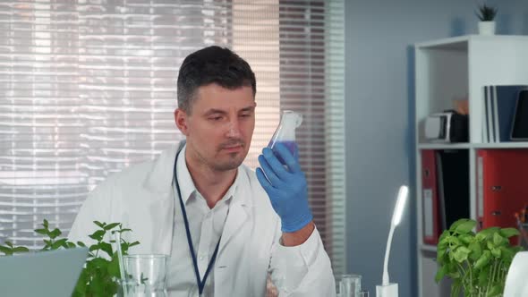 Handsome Research Scientist Observing the Liquid Reaction in Conical Flask During the Experiment