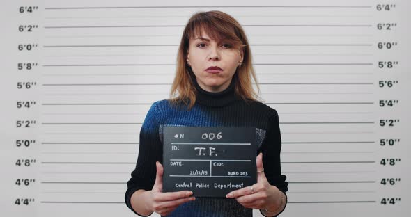 Portrait of Adult Woman with Dyed Hair Holding Sign for Photo in Police Department