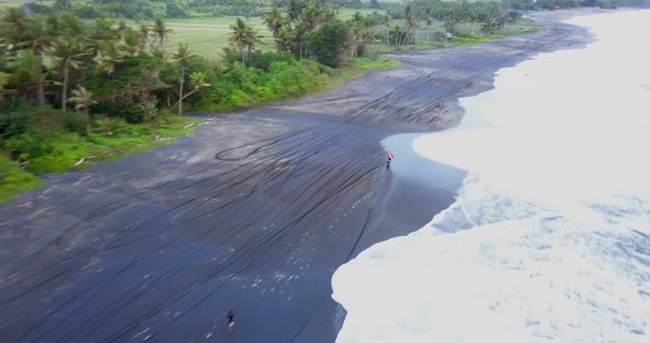 Aerial drone view of a man riding his motocross motorcycle on the beach.