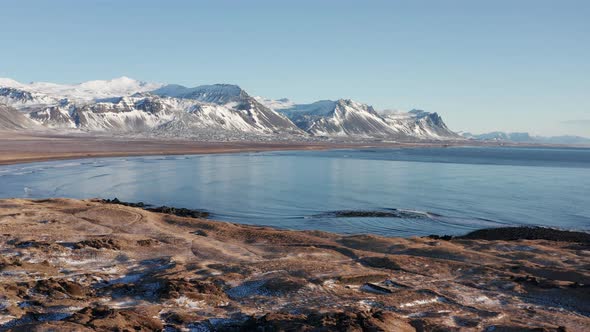 Drone Flight Over Icy Coastline And Sea Towards Mountains