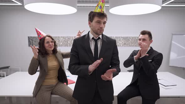 Sarcastic Ironic Handsome Man Standing in Office As Cheerful Colleagues Congratulating Coworker