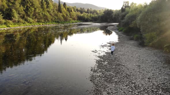 Aerial View of Girl in White Inspired By Beautiful Landscape and Run Near Mountain River