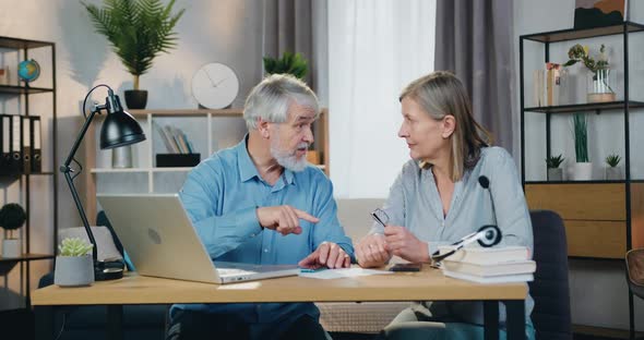 Aged Man Teaching His Pretty Wife How to Use Modern Laptop