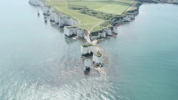 Slow descending reveal drone shot of Old Harry rocks chalk cliffs Dorset UK