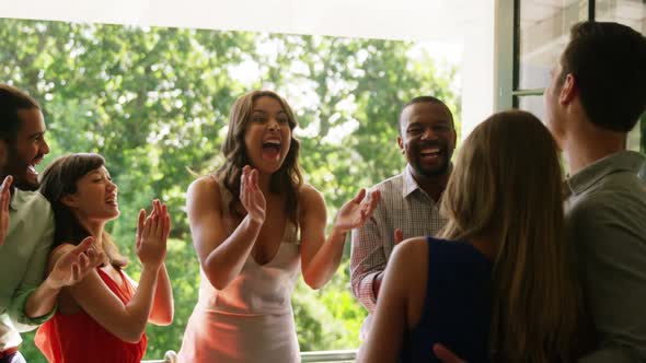 Happy couple embracing while friends applauding during party