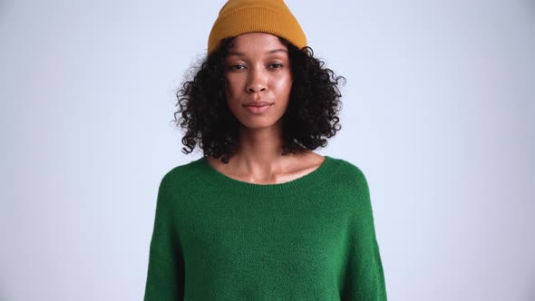 Concentrated curly-haired woman wearing hat looking at the camera