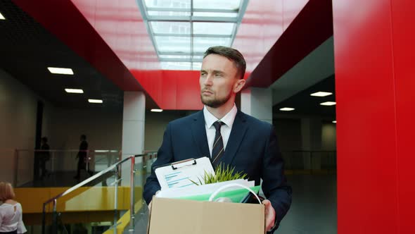 Fired Clerk Unhappy Young Man in Suit Walking in Hall Leaving Workplace with Box of Belongings