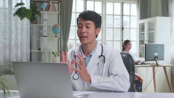 Asian Male Doctor Communicates With Patient By Video Link, Doctor Consults Patient Use Laptop