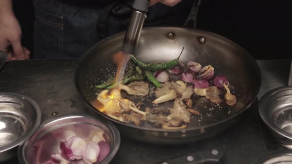 Chef Charring Vegetables In Pan With Blowtorch, close up