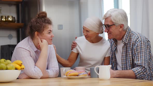 Adult Daughter and Senior Husband Supporting Woman with Cancer Having Coffee Together at Home