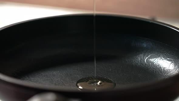 the Process of Pouring Olive Oil Into a Hot Black Pan