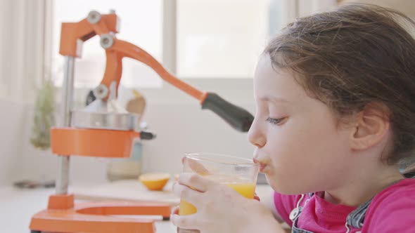 young cute girl drinking a glass of freshly squeezed orange juice