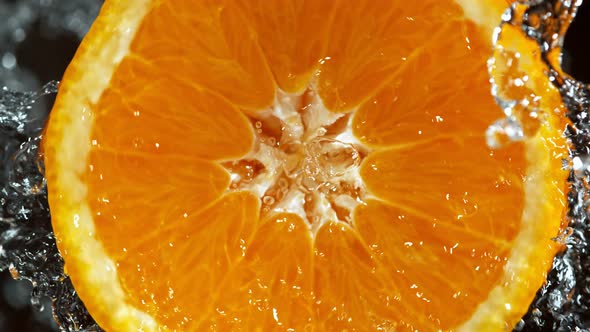 Super Slow Motion Detail Shot of Rotating Fresh Orange Slice and Splashing Water at 1000Fps alt