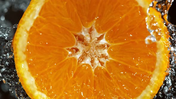 Super Slow Motion Detail Shot of Rotating Fresh Orange Slice and Splashing Water at 1000Fps