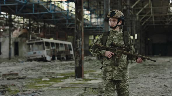 Military Woman with Machine Gun Looking Around Factory