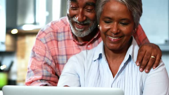 Senior couple using laptop in the kitchen