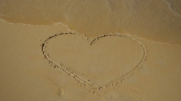 Sea Wave Washes a Painted Heart on the Sand