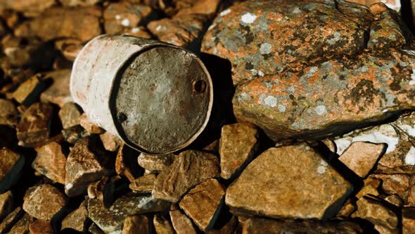 Rusty Destroyed Metal Barrel on Beach Rocks