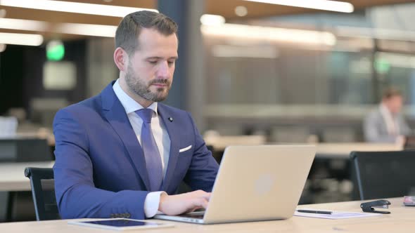 Middle Aged Businessman Working on Laptop in Office