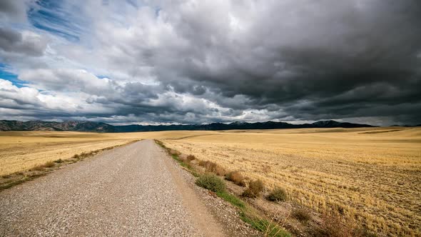 Time lapse of road through rolling hills of cut straw with moody sky