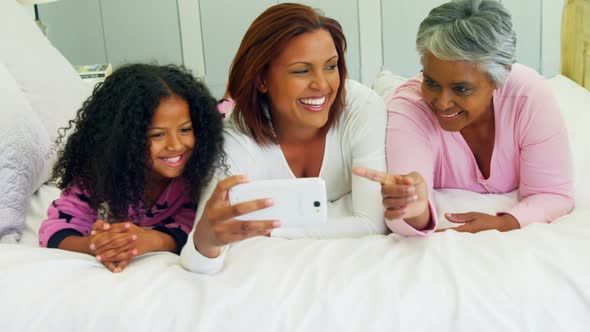 Family reviewing photos on mobile phone in bedroom 4k