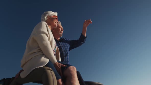 Senior couple sitting on a car