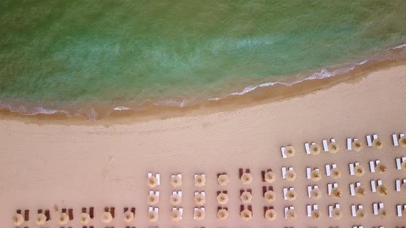 Aerial View of an Amazing Empty Sand Beach with Straw Beach Umbrellas and Turquoise Clear Water