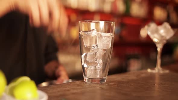 Bartender preparing cocktail by first squeezing fresh lime over ice