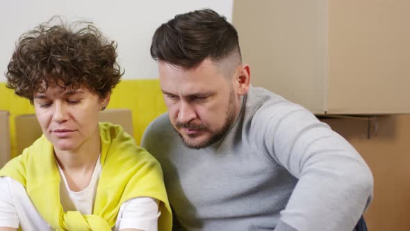 Relaxed Middle-Aged Caucasian Couple Using Laptop in New House