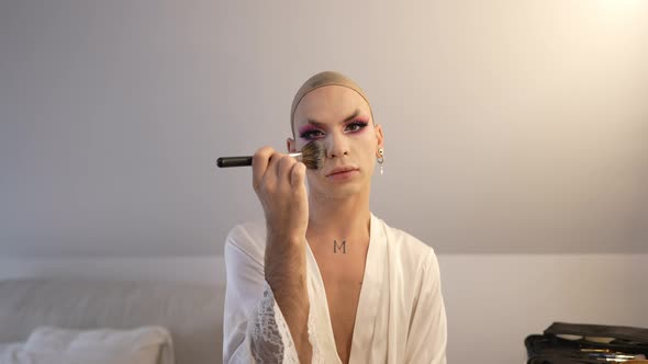 Medium Shot Portrait of Confident Transgender Woman Applying Face Powder in Slow Motion Looking at