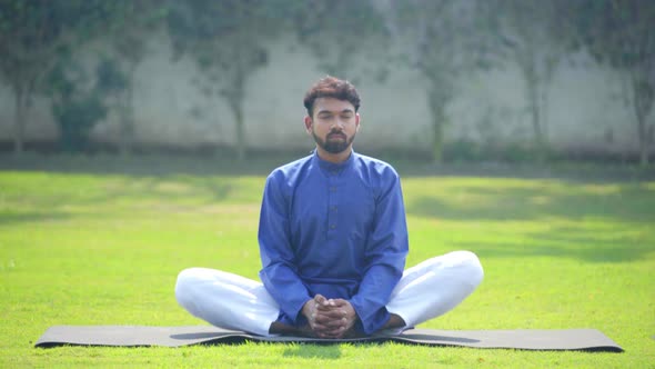 Indian man doing Butterfly Yoga Pose or Badhakonasana in an Indian traditional outfit Kurta Pajama