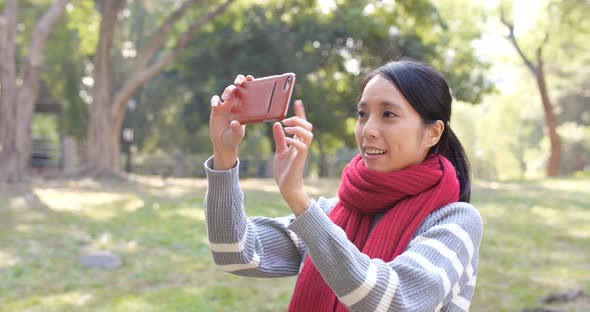 Woman using cellphone for taking photo in park