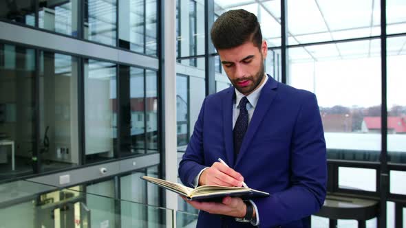 Businessman writing in diary at office