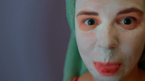 Woman with Towel on Head and Mask on Face Shows Tongue