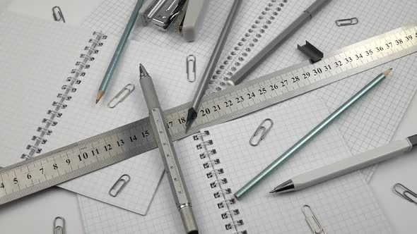 Various stationery in gray are laid out on the different paper notepad, slow motion