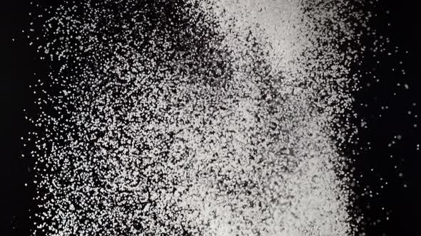 Dusting flour on black background. Slow Motion.