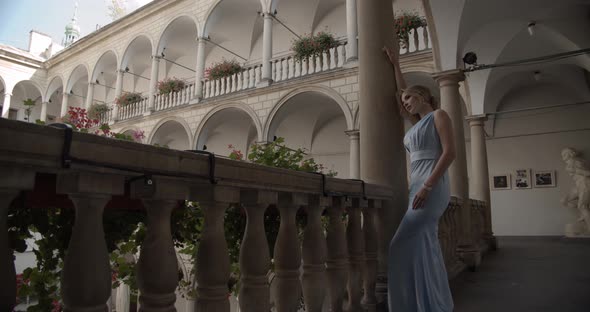 Girl In A Festive Dress Stands Near The Column In The Castle