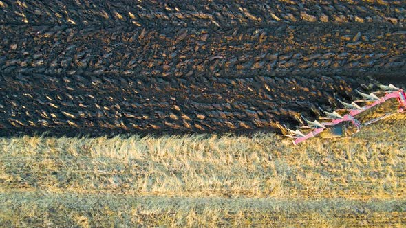 Aerial view of a tractor plowing agricultural farm field.