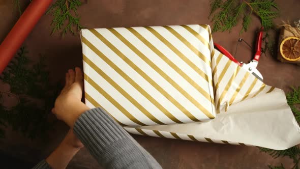 Hands Wrapping Christmas Gift Box with Paper