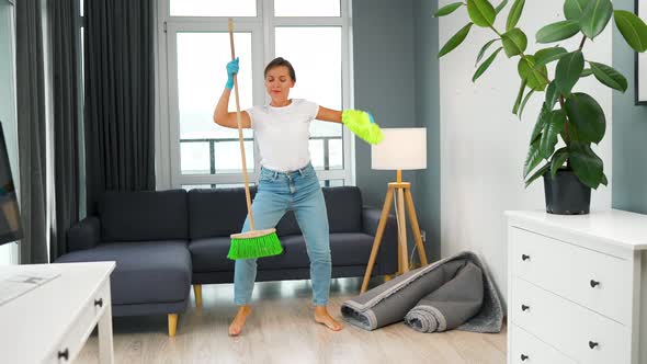 Woman in Headphones Cleaning the House and Having Fun Dancing with a Broom and Washcloth