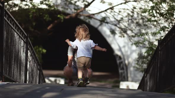 a two-year-old child runs in the park, runs to meet his parents