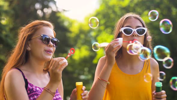 Teenage Girls Blowing Bubbles in Summer Park