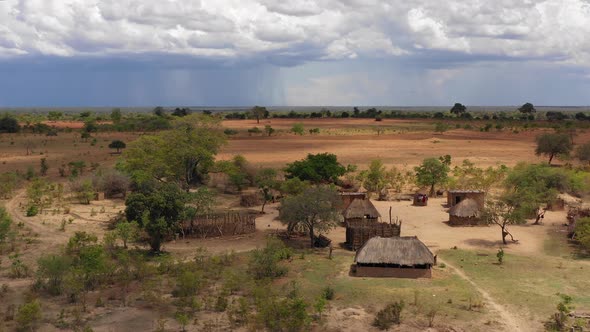 Flying by a remote African village in southern Zambia with rain clouds in the background. Africa. 4K