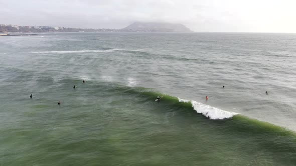 4k aerial video shot during daytime of a surfer catching and riding a wave on the coastal waters of