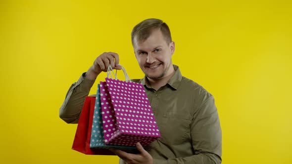 Man Raising Shopping Bags, Looking Satisfied with Purchase, Enjoying Discounts on Black Friday